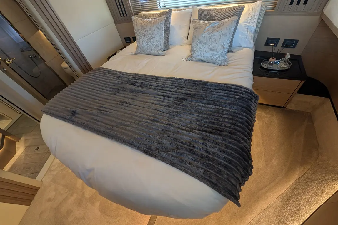 Luxurious bedroom featuring a double bed with plush grey throw, decorative pillows, and a stylish bedside table.
